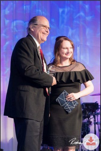 A man in a suit and tie is shaking hands with a woman in a black dress.