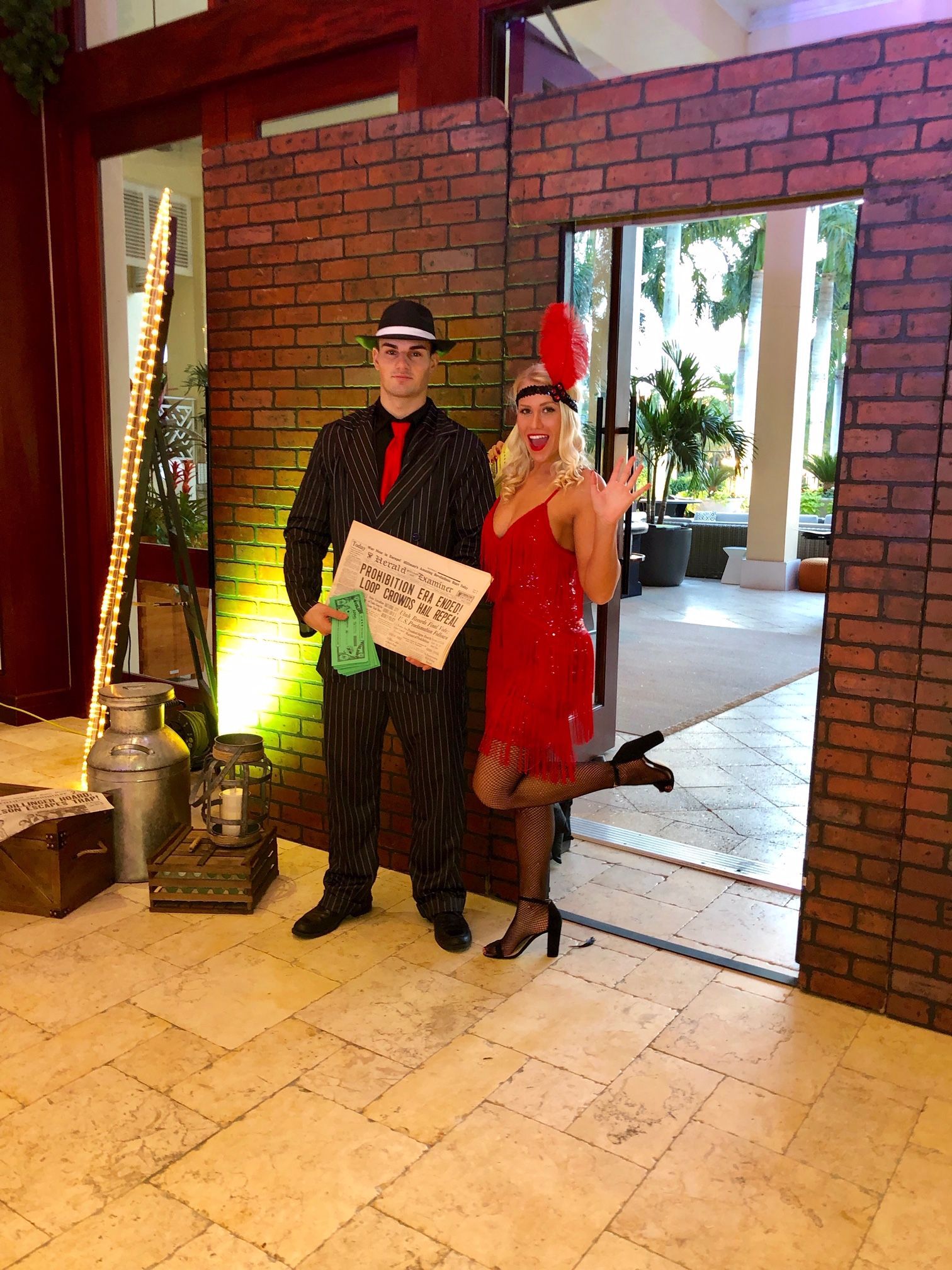 A man and a woman are standing next to each other in front of a brick wall.