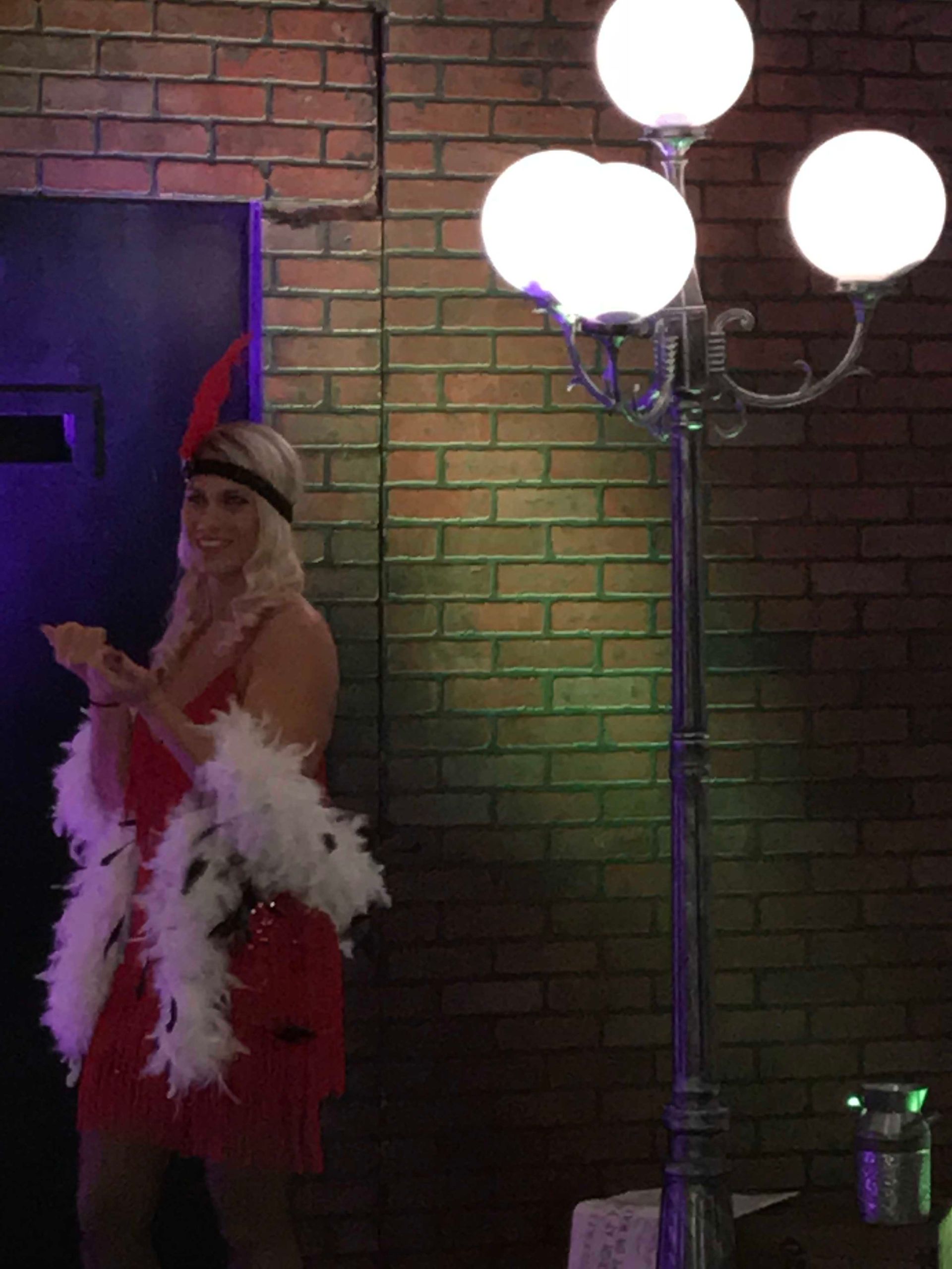 A woman in a red dress is standing next to a lamp post.