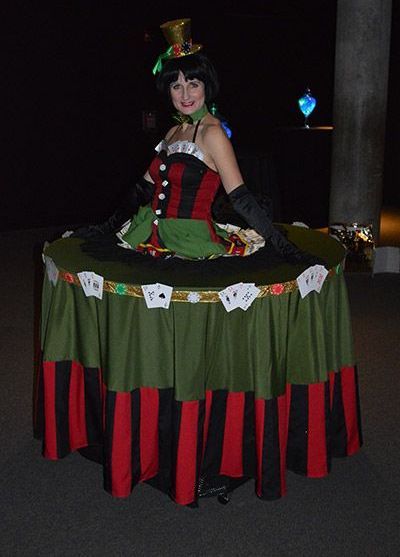 A woman in a costume is standing on a table with playing cards on it