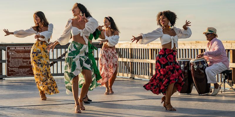 A group of women are dancing in front of a man playing a drum.