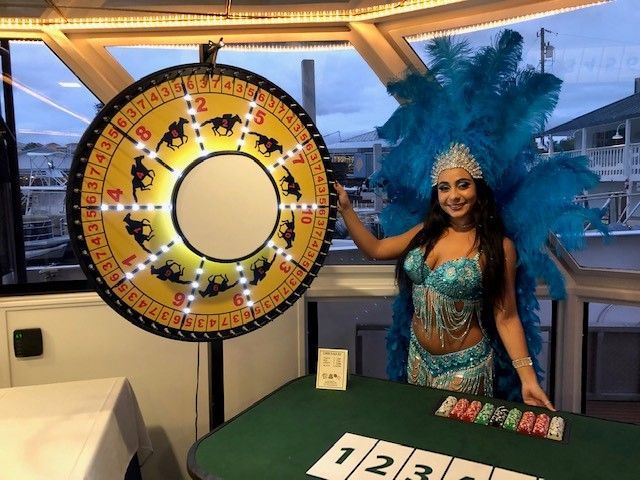 A woman in a carnival costume is standing in front of a roulette wheel