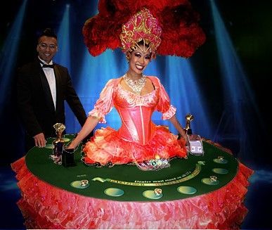 A woman in a pink dress is sitting at a table with a man in a tuxedo standing behind her