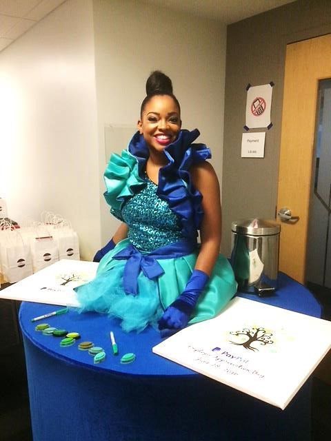 A woman in a blue and green dress sits at a table