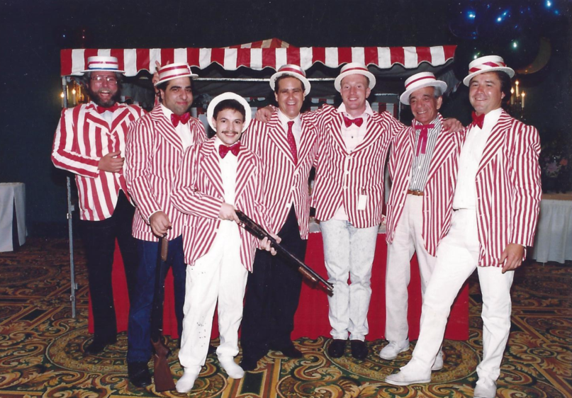 A group of men in red and white striped suits and hats pose for a photo