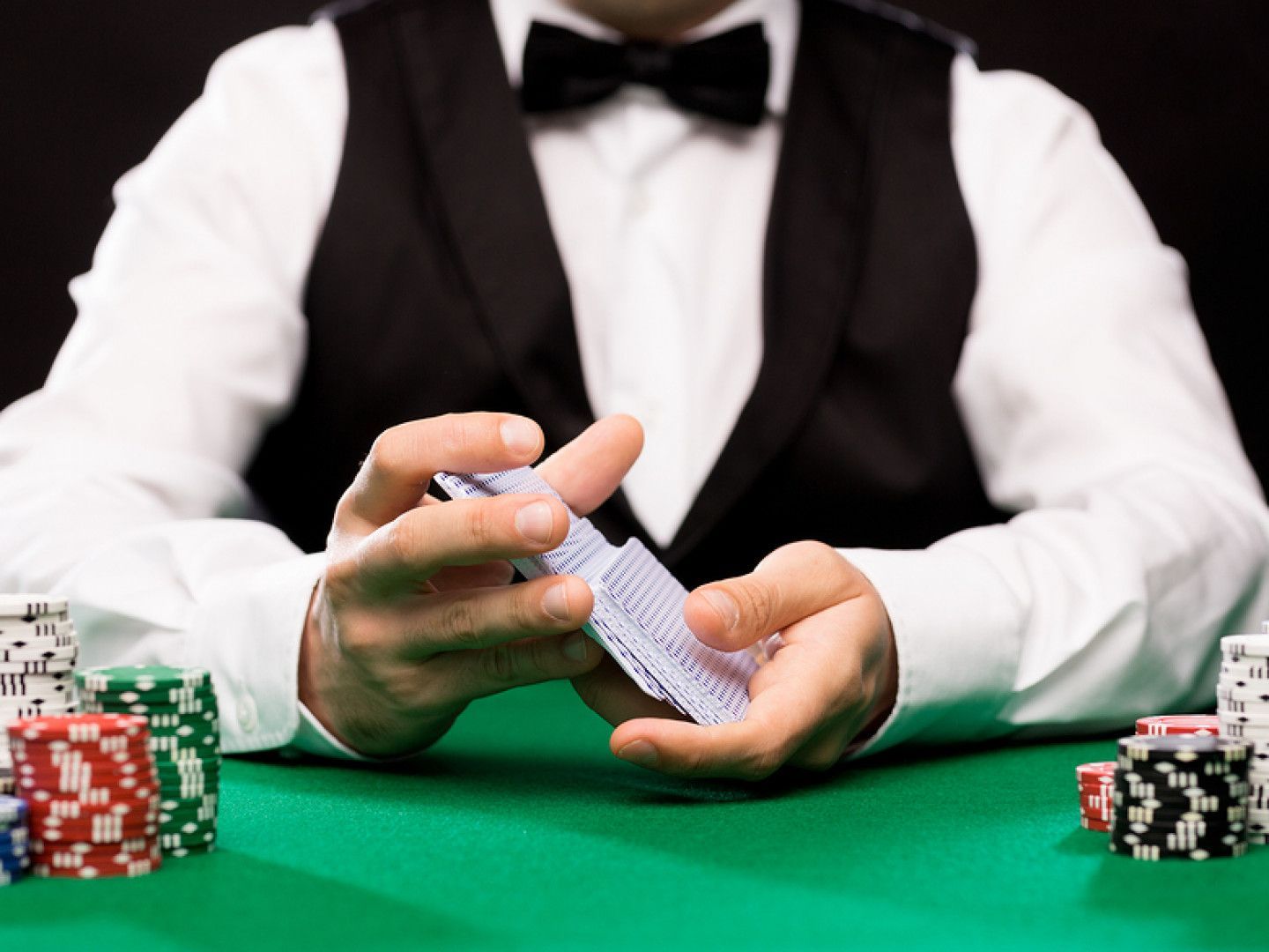 A man in a tuxedo is holding a pair of playing cards in his hands.