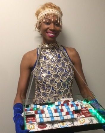 A woman in a dress is holding a tray of cigarettes