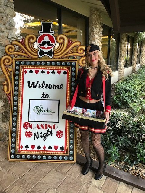 A woman is standing in front of a sign that says welcome to casino night