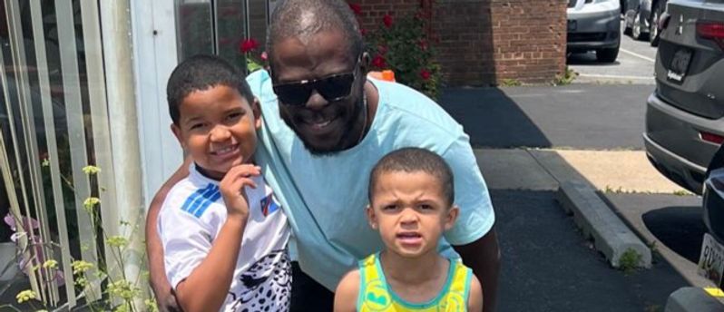 A man is standing next to two young boys on a sidewalk.