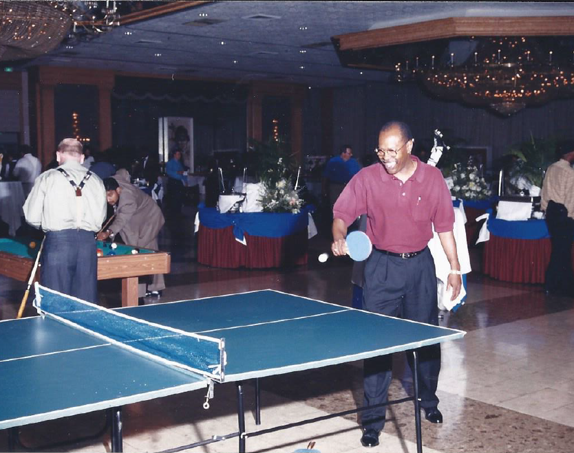 A man is playing ping pong in a large room