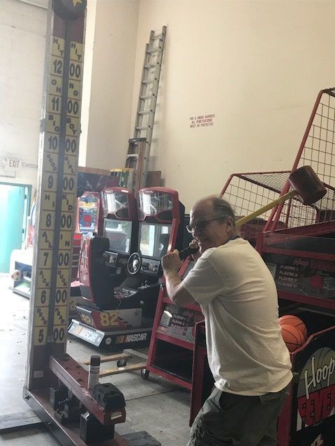 A man in a white shirt is standing in front of a giant hammer