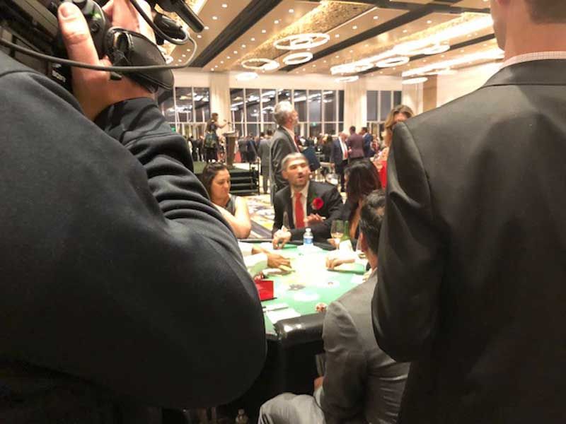 A man is taking a picture of a group of people playing poker