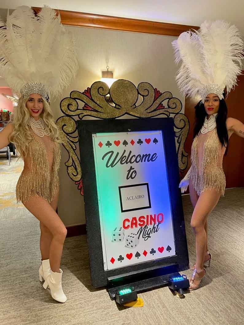 Two women are standing in front of a welcome to casino sign.