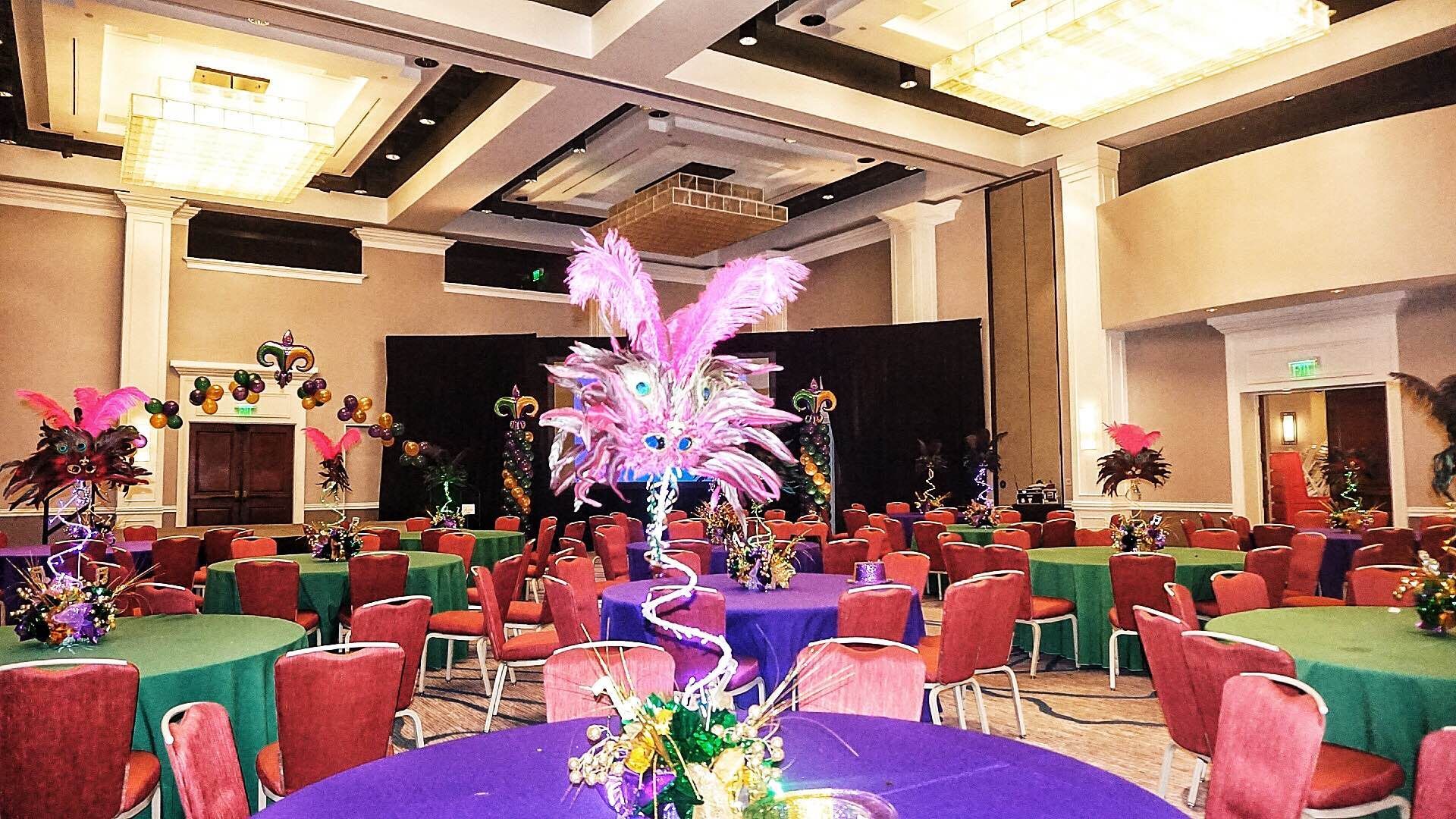 A large room with tables and chairs decorated for mardi gras