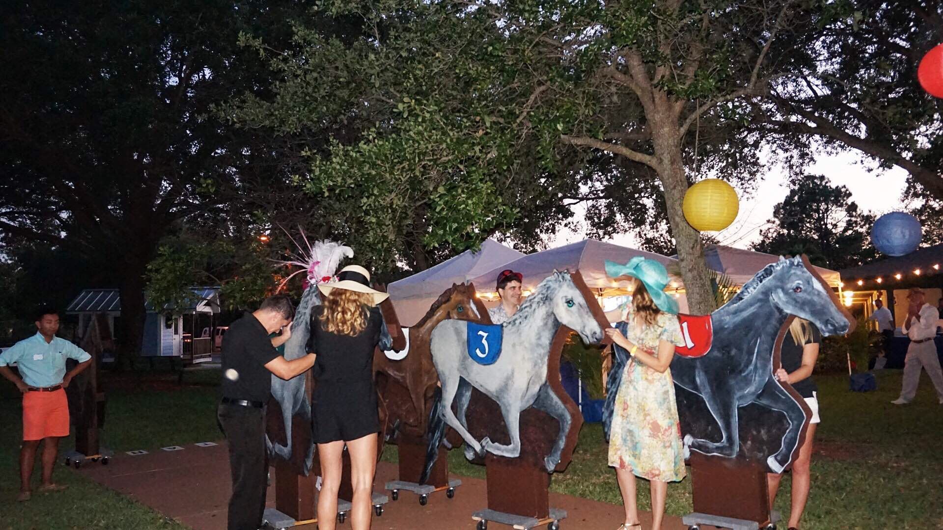A group of people are standing in front of a carousel horse with the number 1 on it