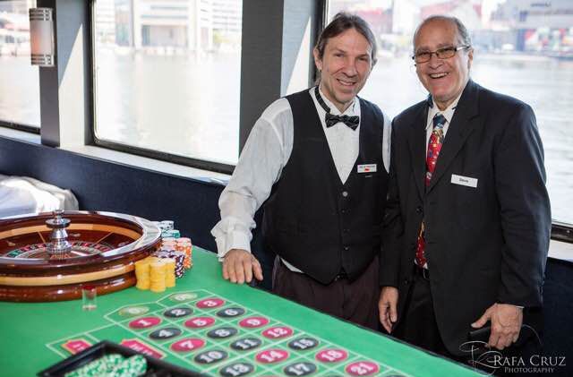 Two men are standing next to a roulette table in a casino.