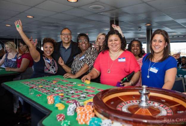 A group of people are standing around a roulette table.