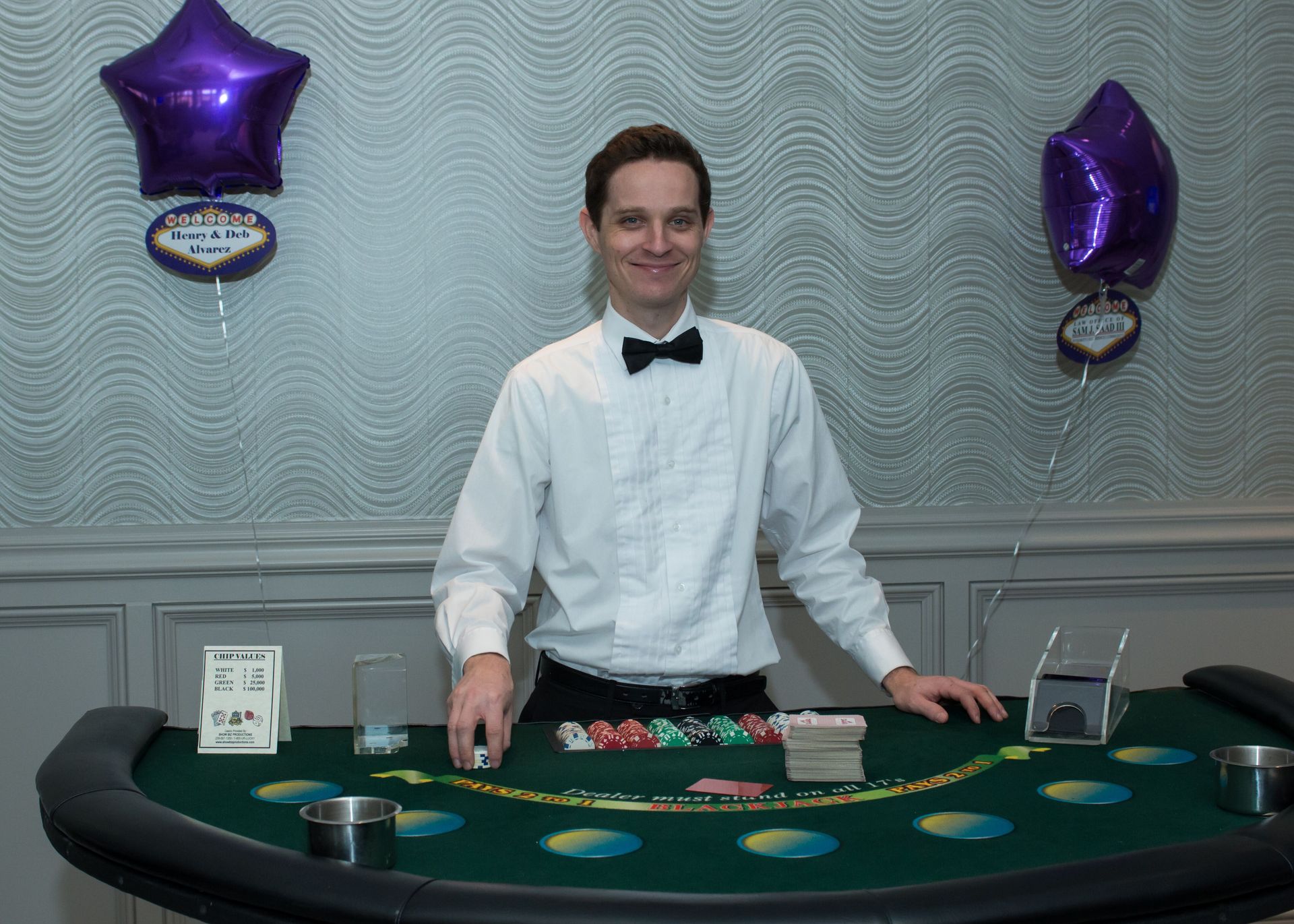 A man in a tuxedo is standing in front of a blackjack table.
