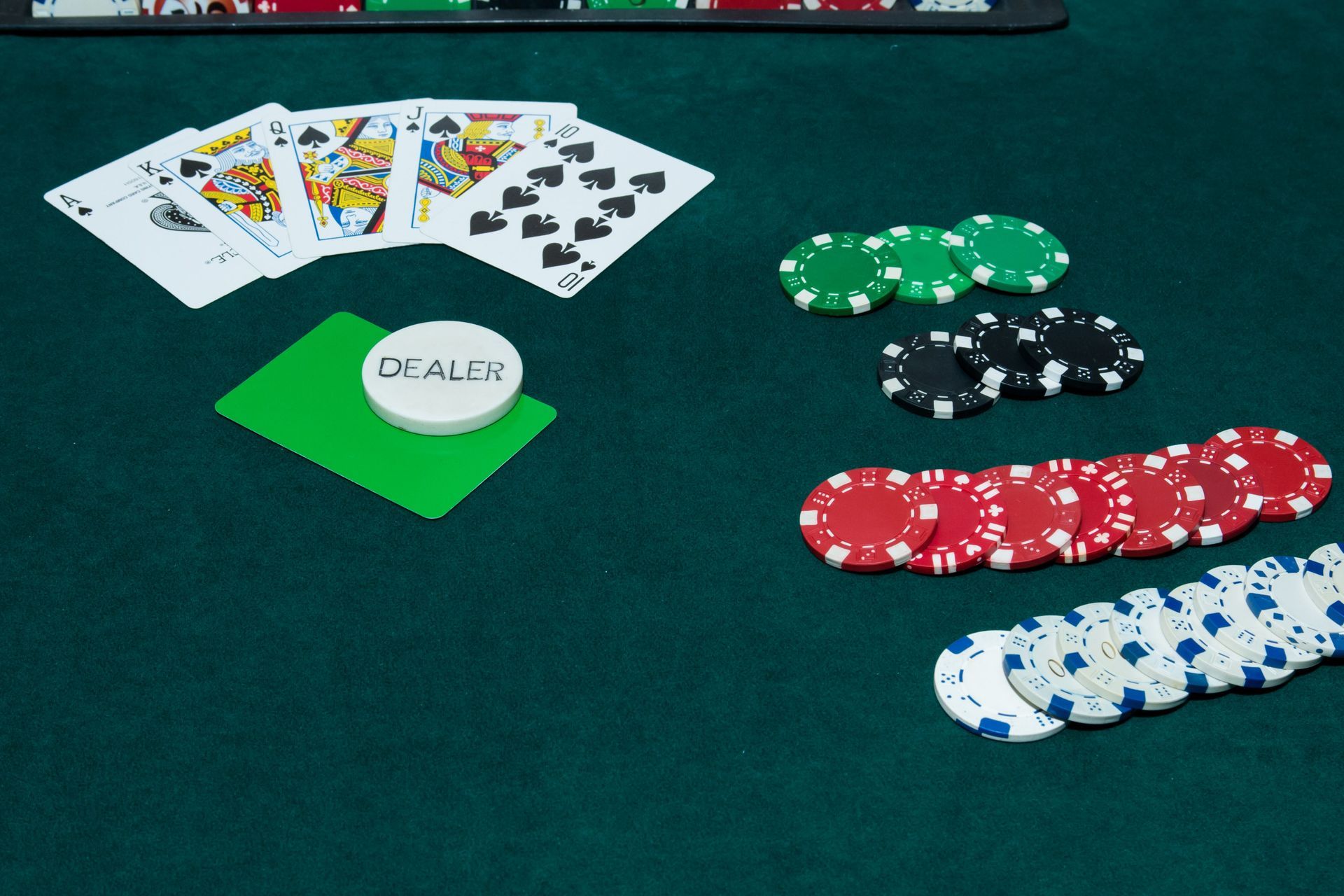 Playing cards and poker chips on a table with a dealer chip