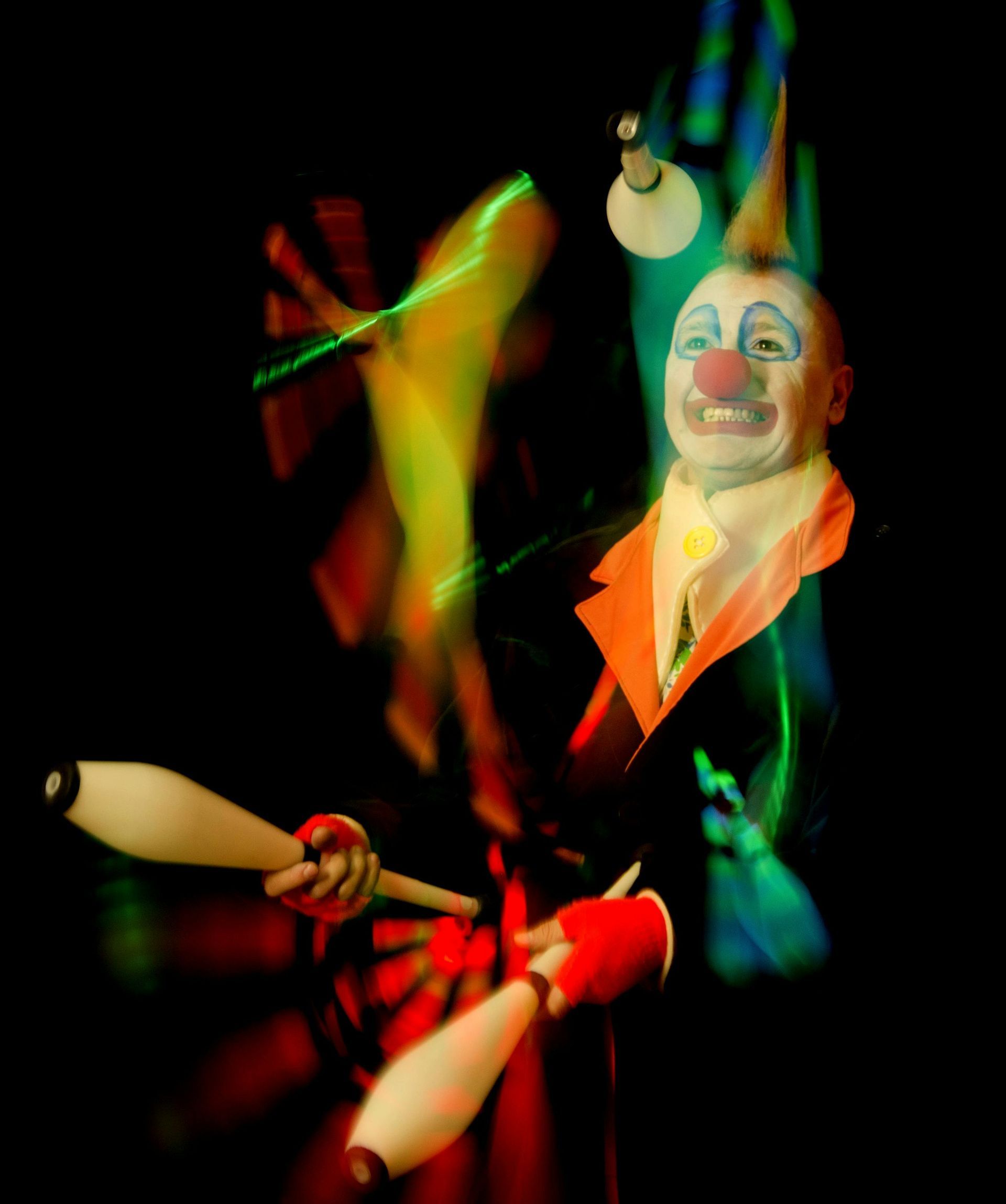 A clown is juggling a pair of juggling pins