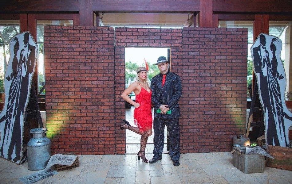 A man and a woman are standing in front of a brick wall.