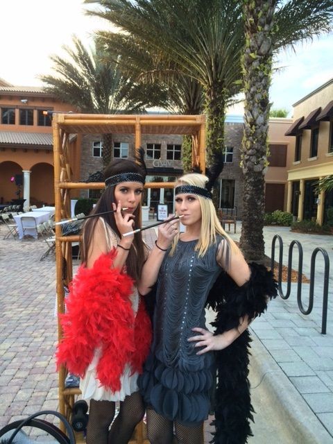 Two women dressed in flapper costumes are standing next to each other