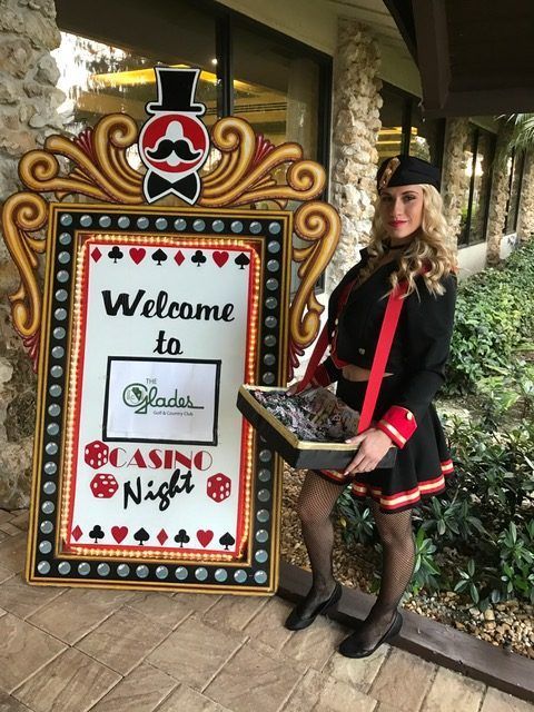 A woman is standing in front of a sign that says welcome to casino night