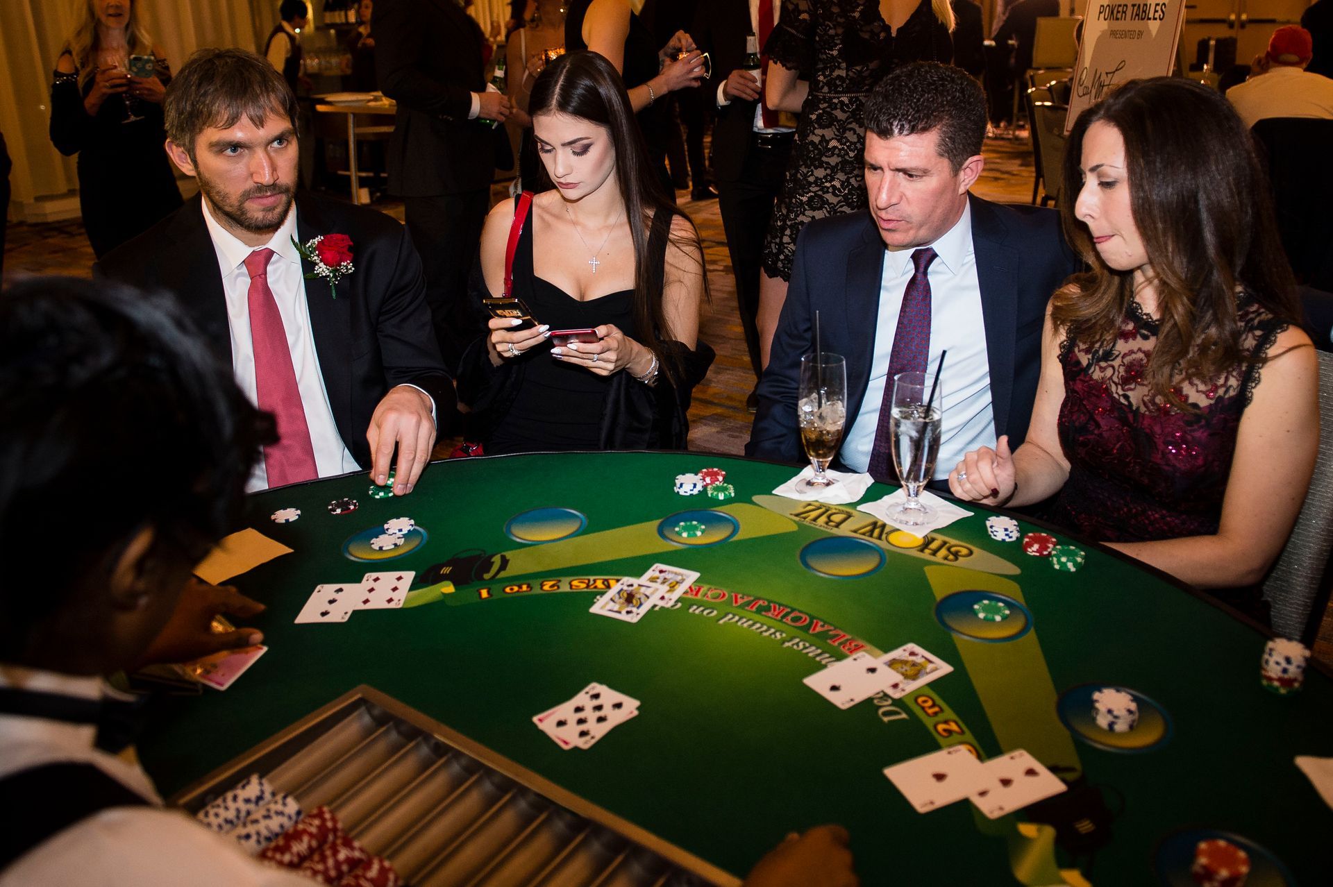 A group of people are sitting around a table playing a game of blackjack.