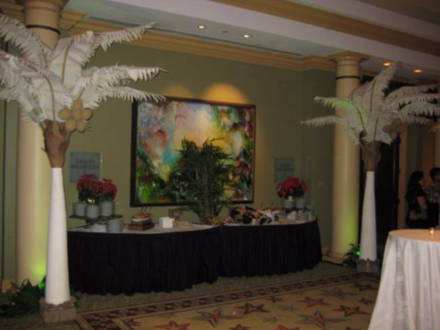 A room with tables and palm trees and a painting on the wall