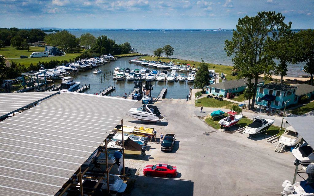 Boats docked in a harbor, with a boat ramp in the foreground, near a large body of water.