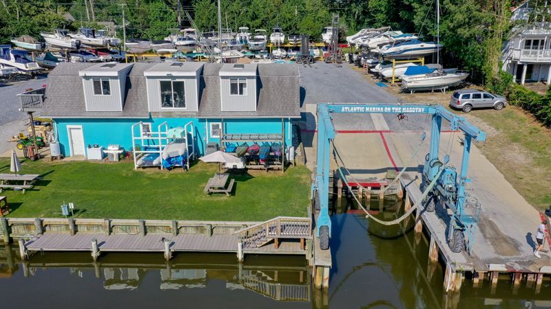 Aqua building with boats on a boat lift, docks, and boats in the background.