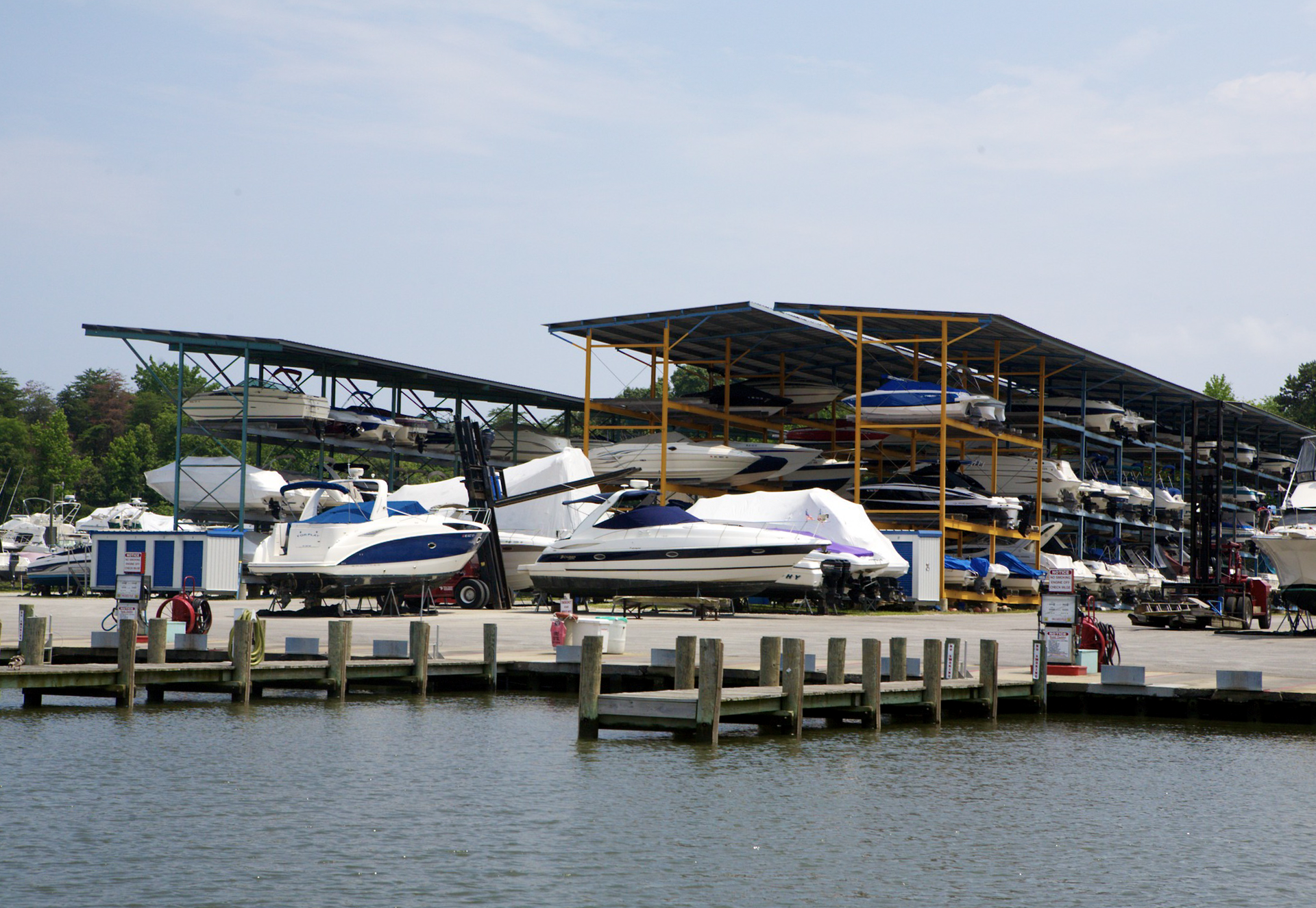 Boats stored on racks under covered docks at a marina.