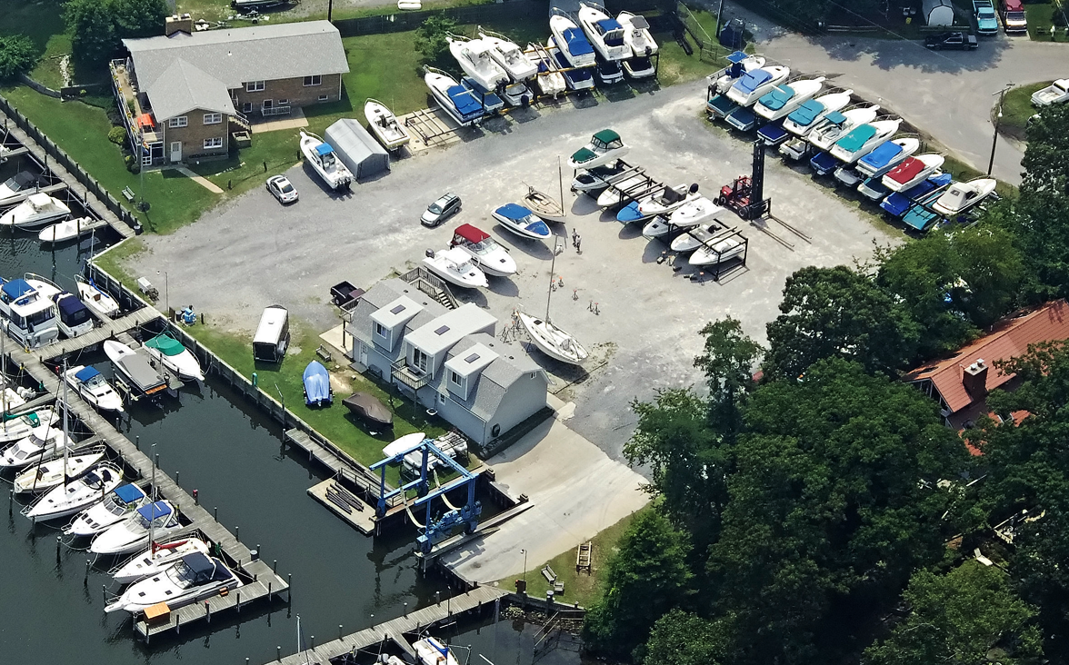 Aerial view of a marina with boats docked at piers, storage racks, and on land.