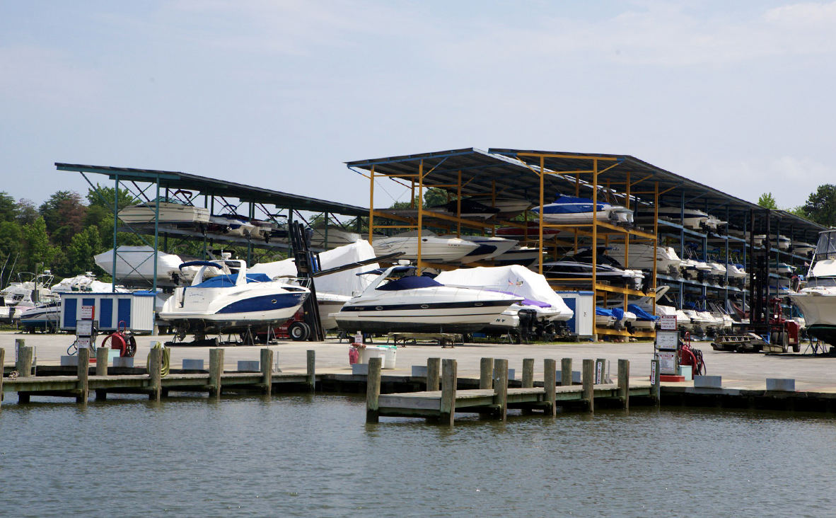 Boats stored on racks at a marina dock. Blue sky, boats covered in white and blue covers.