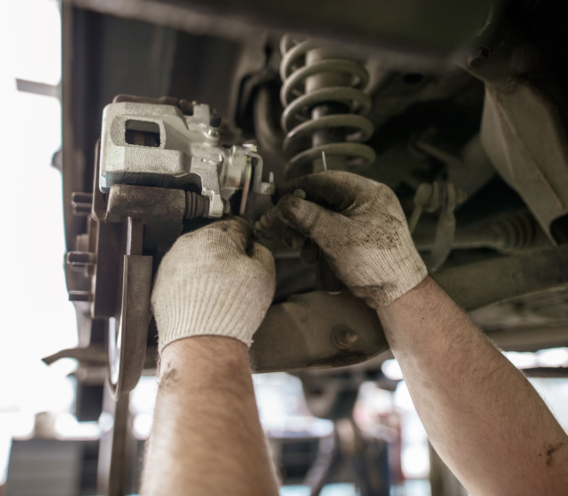 Mechanic wearing safety gear, painting a white car.