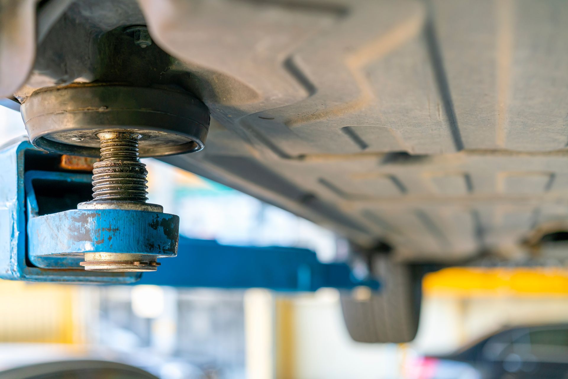 Auto body worker sanding car hood with respirator and safety glasses on.