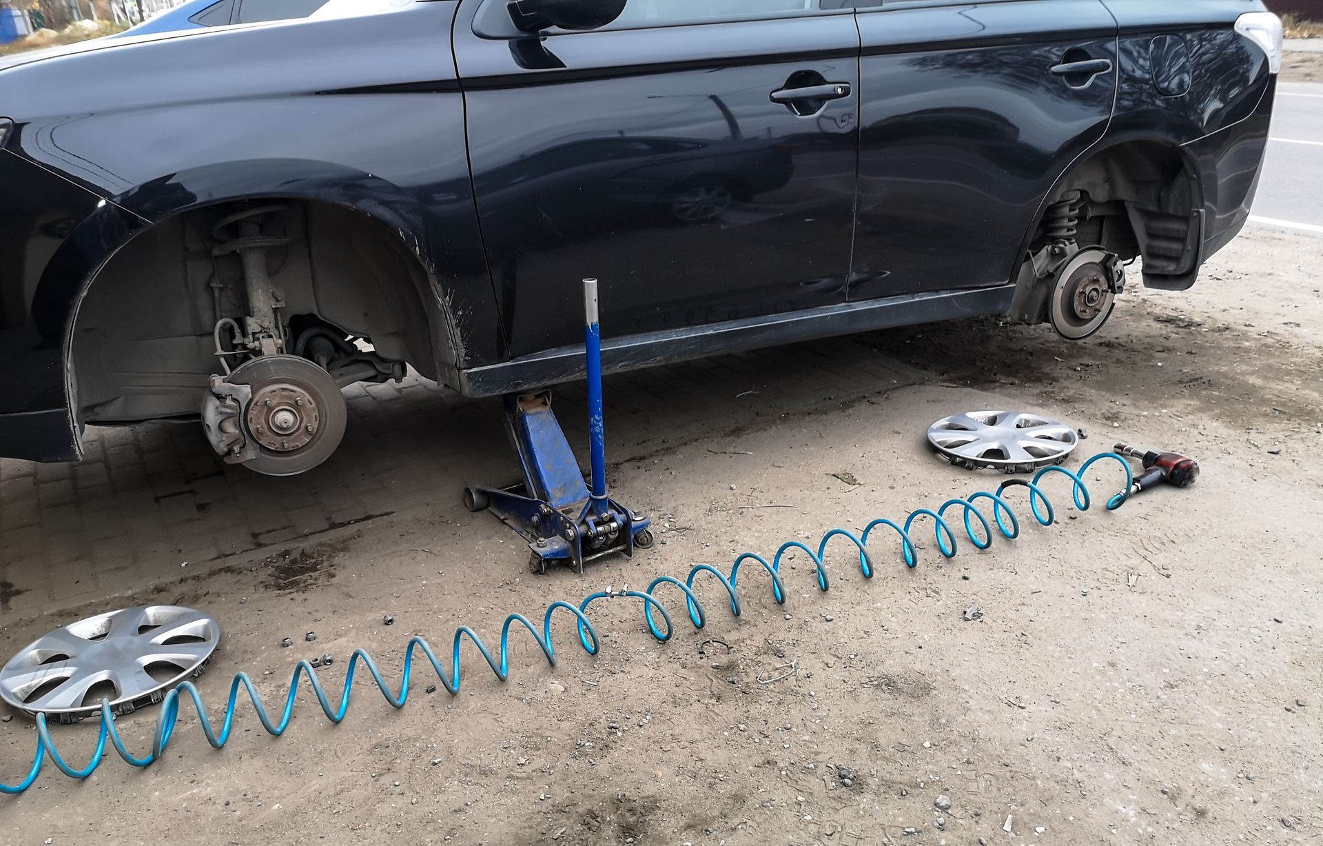 Man using a sander on a red car in a garage.