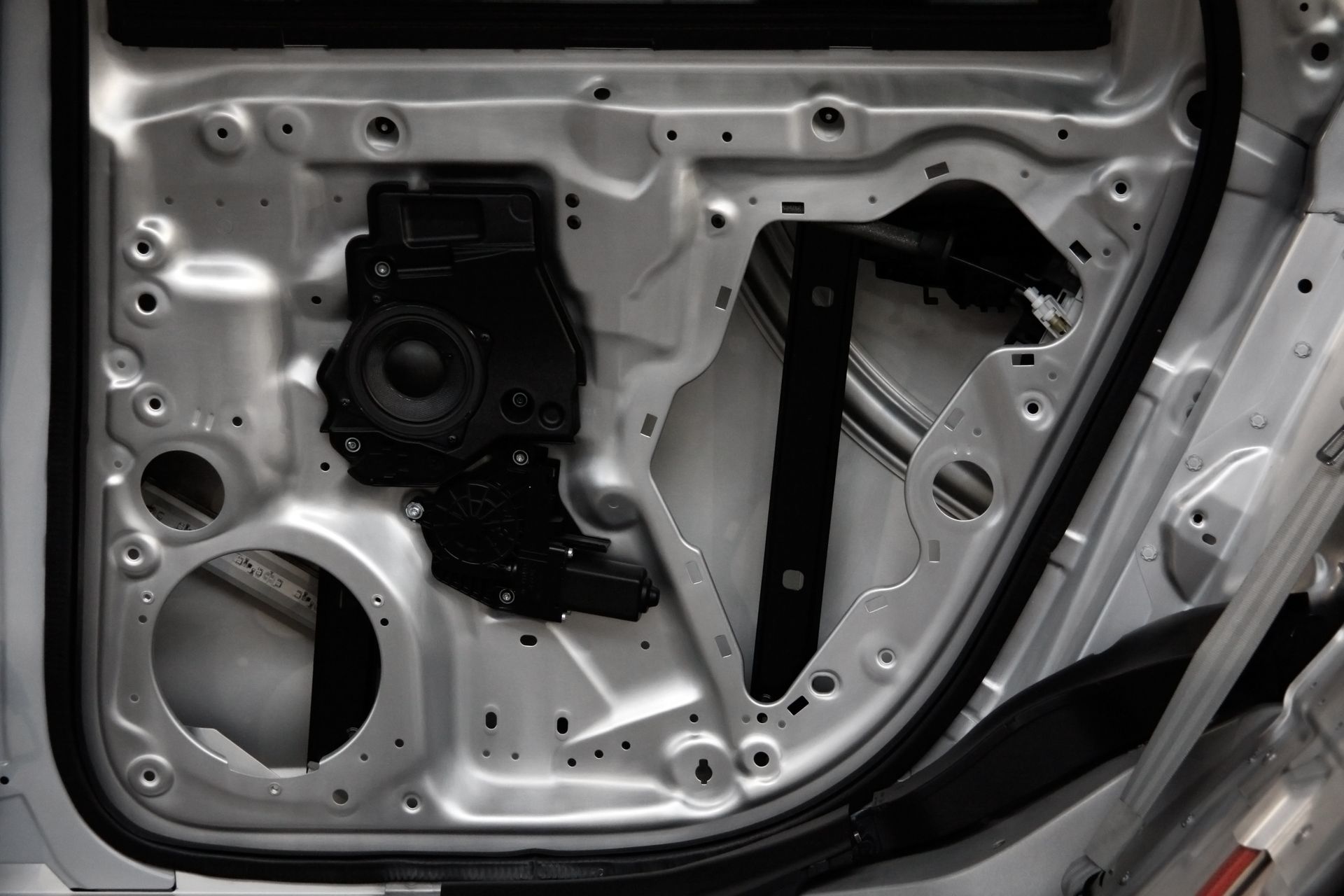 Hands wearing blue gloves sanding a car's roof in a body shop.