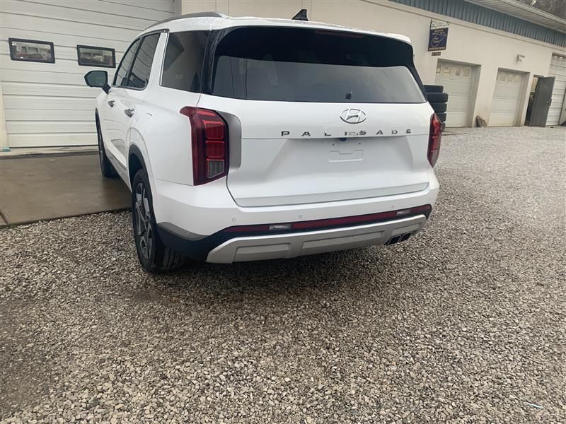 White Hyundai Palisade SUV parked on gravel, facing away.