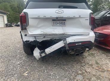 Mechanic in blue jumpsuit using a wrench on a car engine.