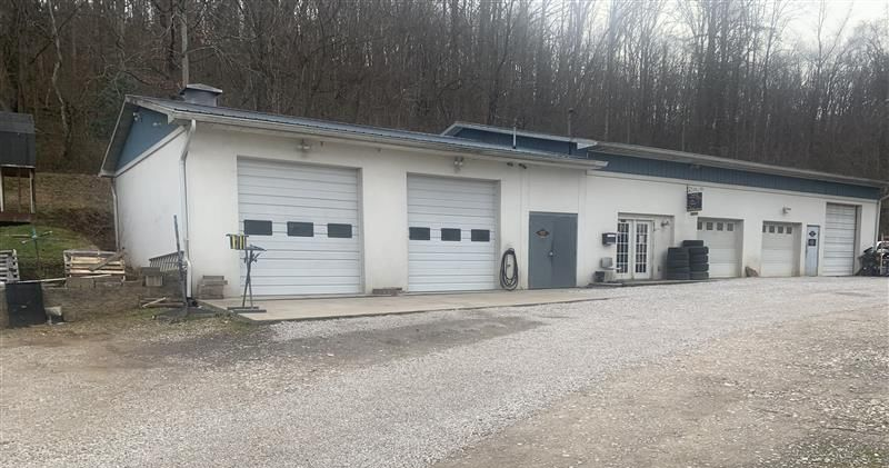 Two cars, a black sedan and white hatchback, damaged in a rear-end collision on a road.