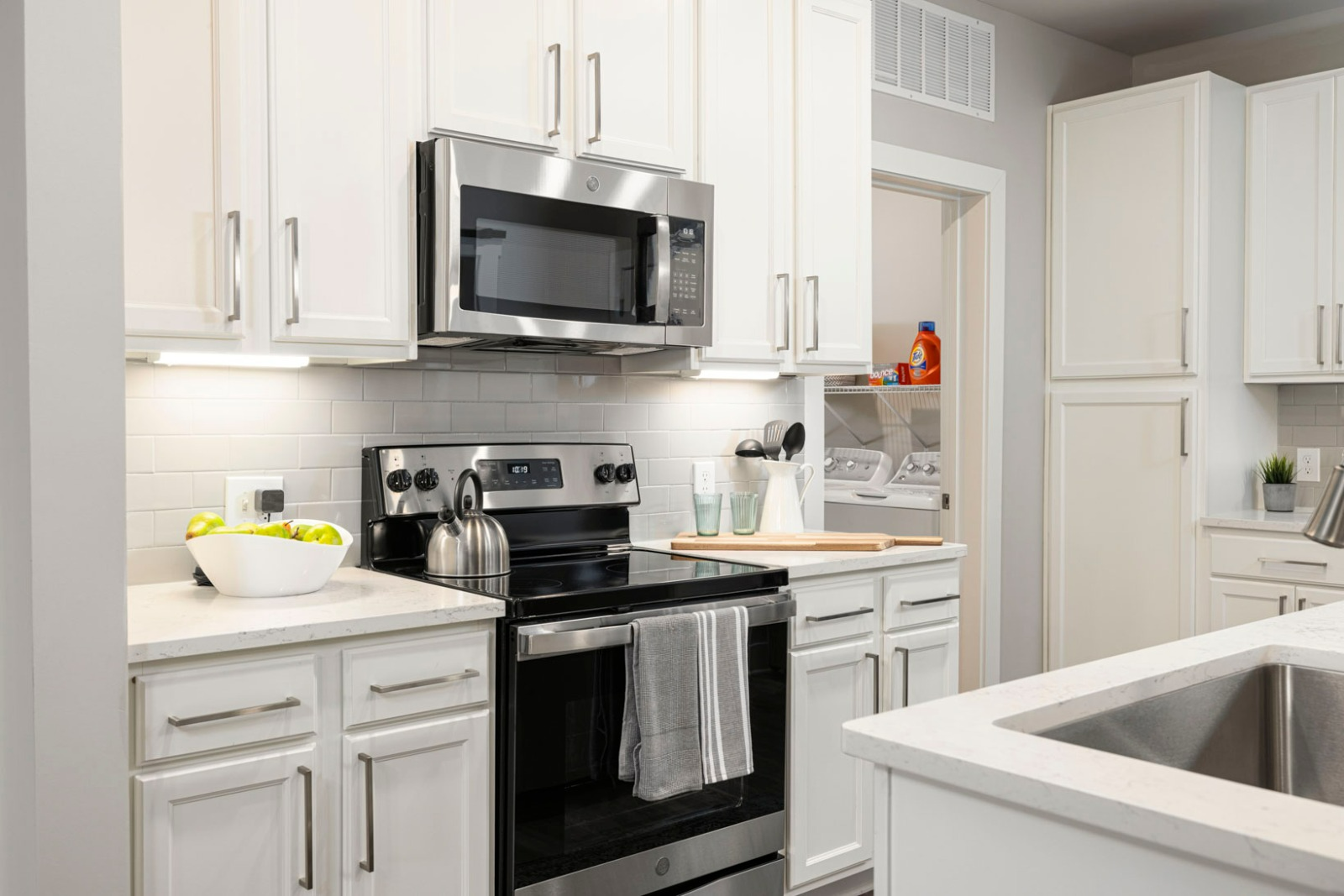A kitchen with white cabinets , stainless steel appliances , and a sink.
