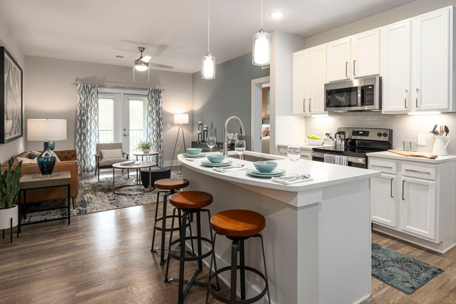 A kitchen with a large island and stools in a living room.
