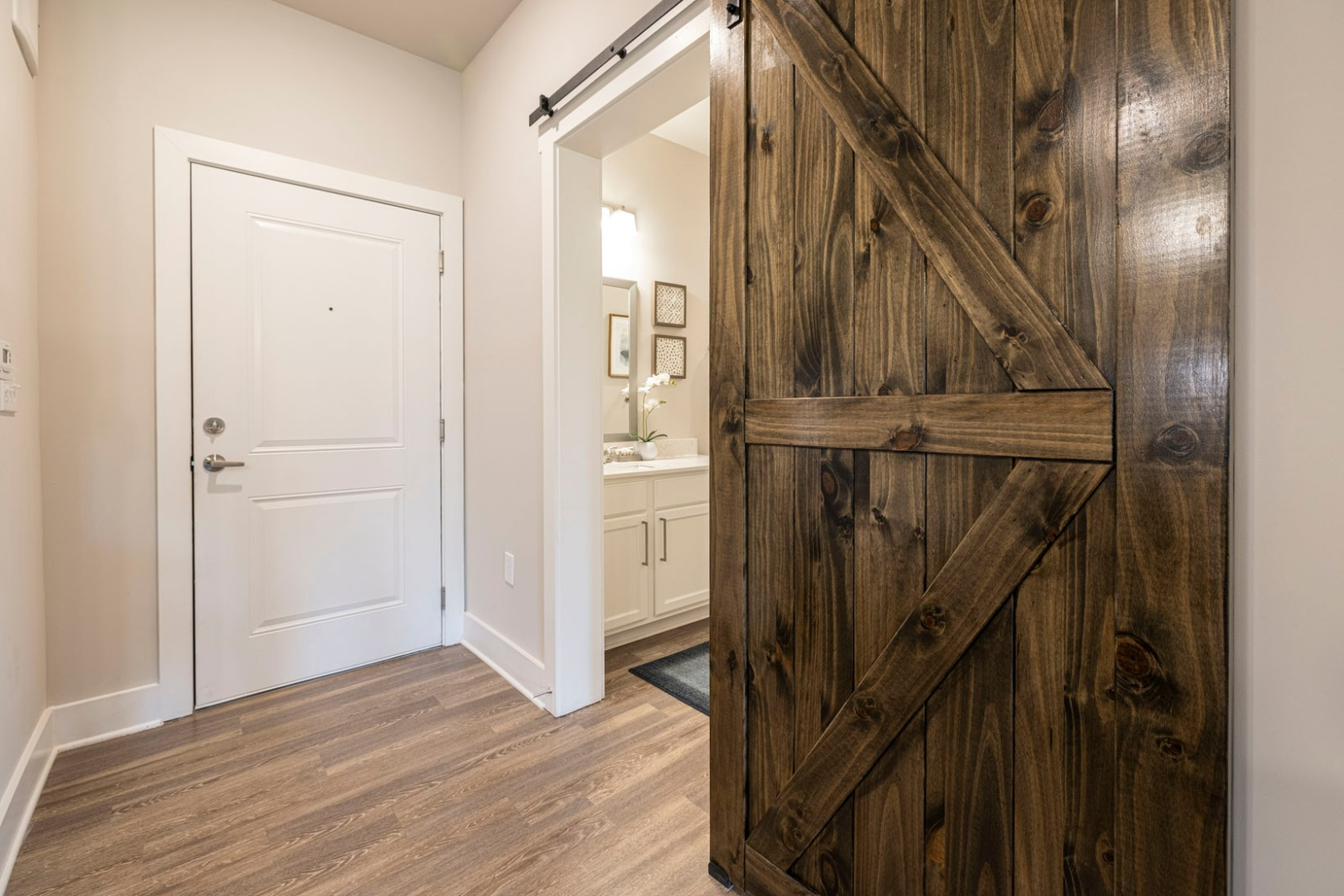 A hallway with a sliding barn door leading to a bathroom.