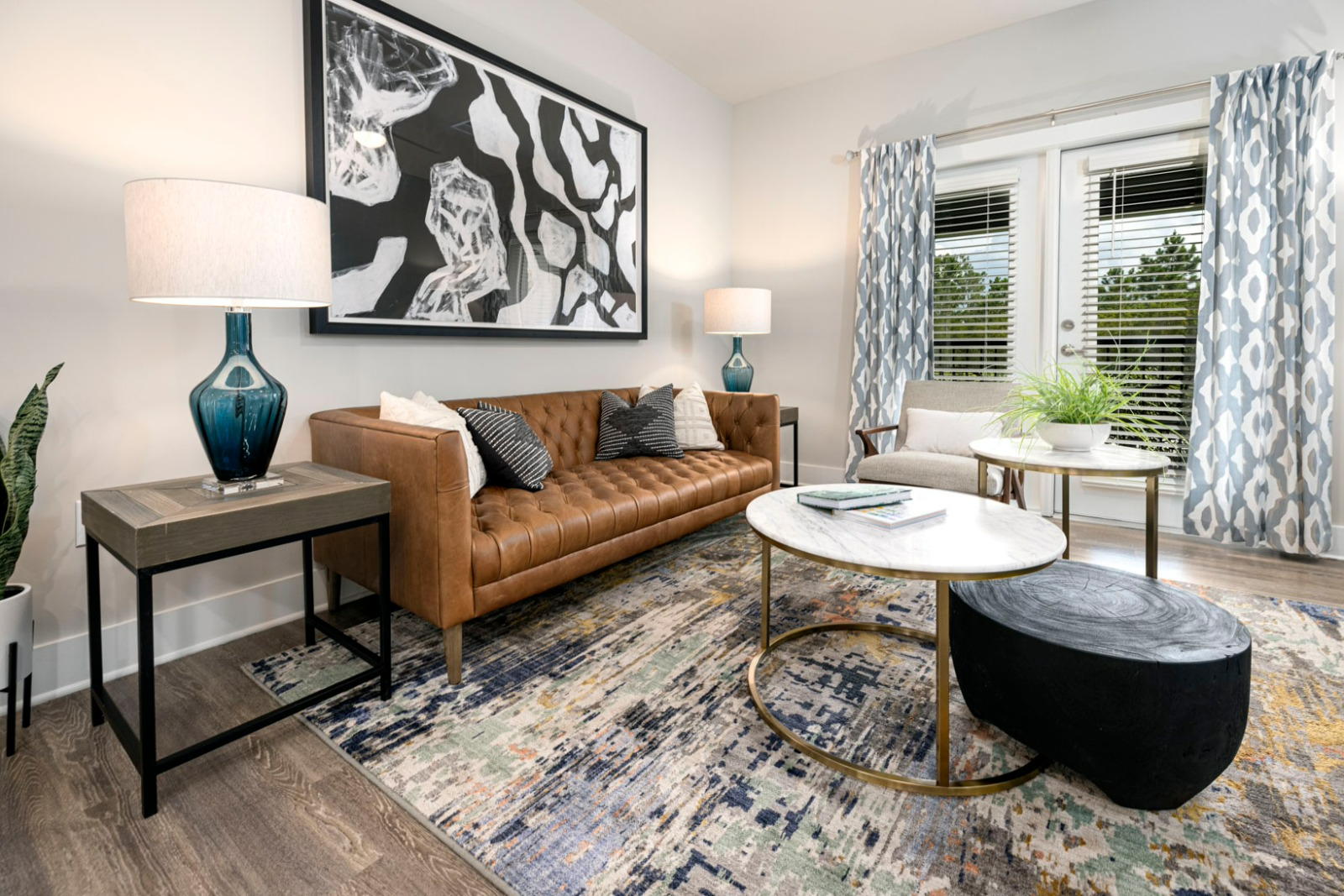 A living room with a couch , coffee table , ottoman and a painting on the wall.