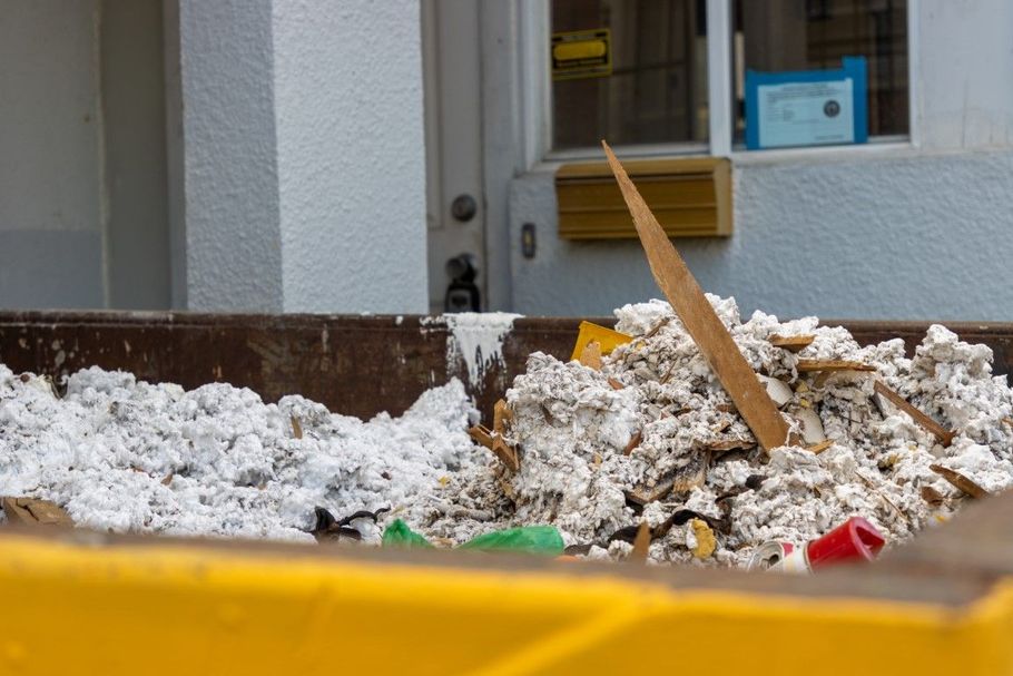 Snow and debris piled beside a building, with yellow barrier tape in the foreground.