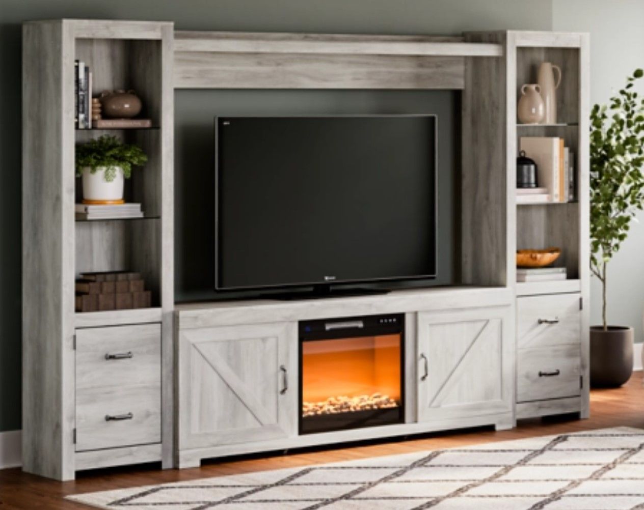 White TV entertainment center with fireplace, shelves, and TV.
