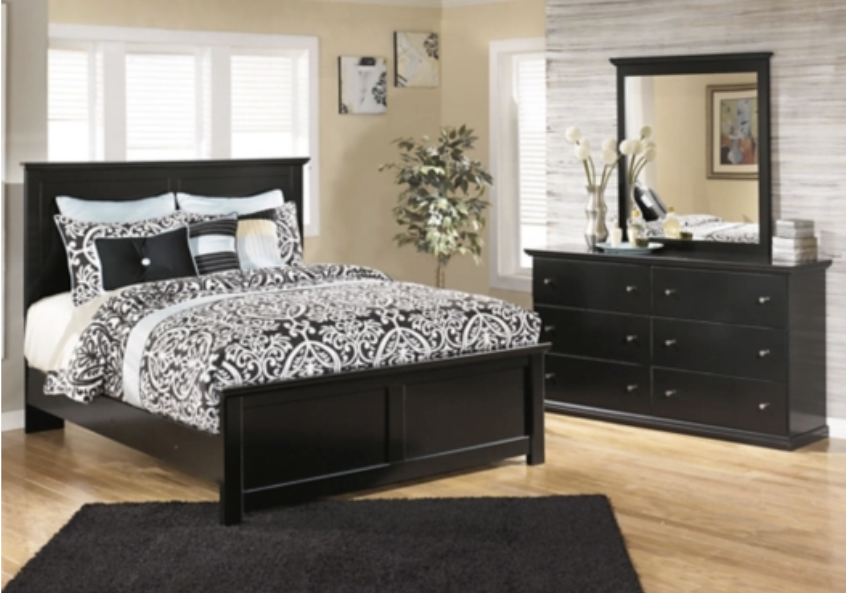 Black bedroom set with bed, dresser, and mirror in a room with a rug and window.