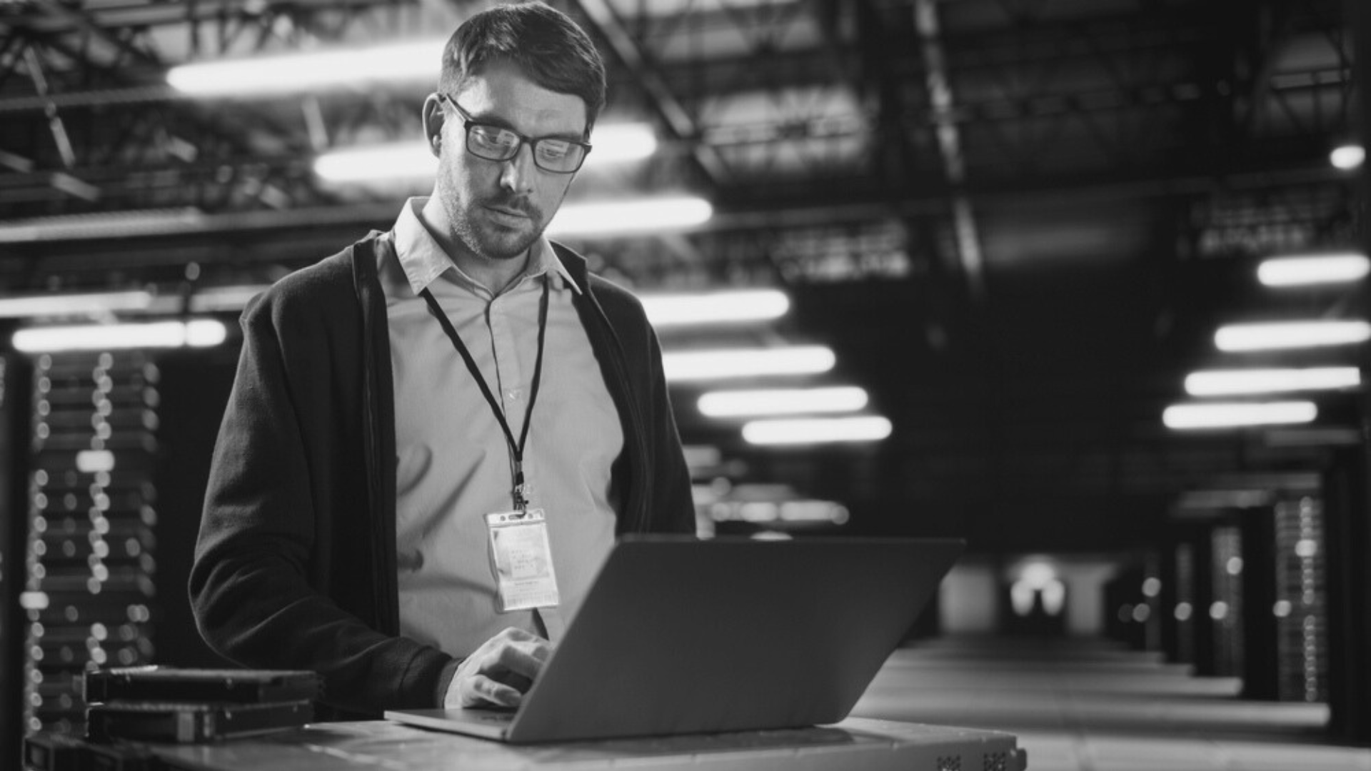 A man is using a laptop computer in a warehouse.