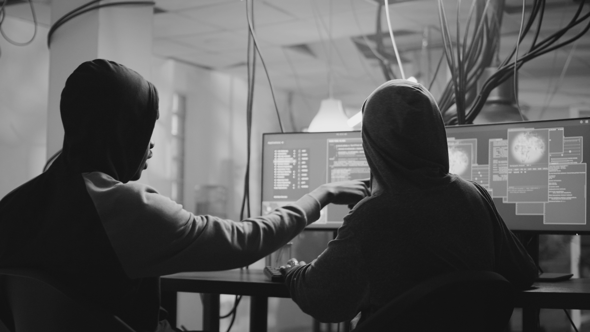 Two men in hoodies are looking at a computer screen.